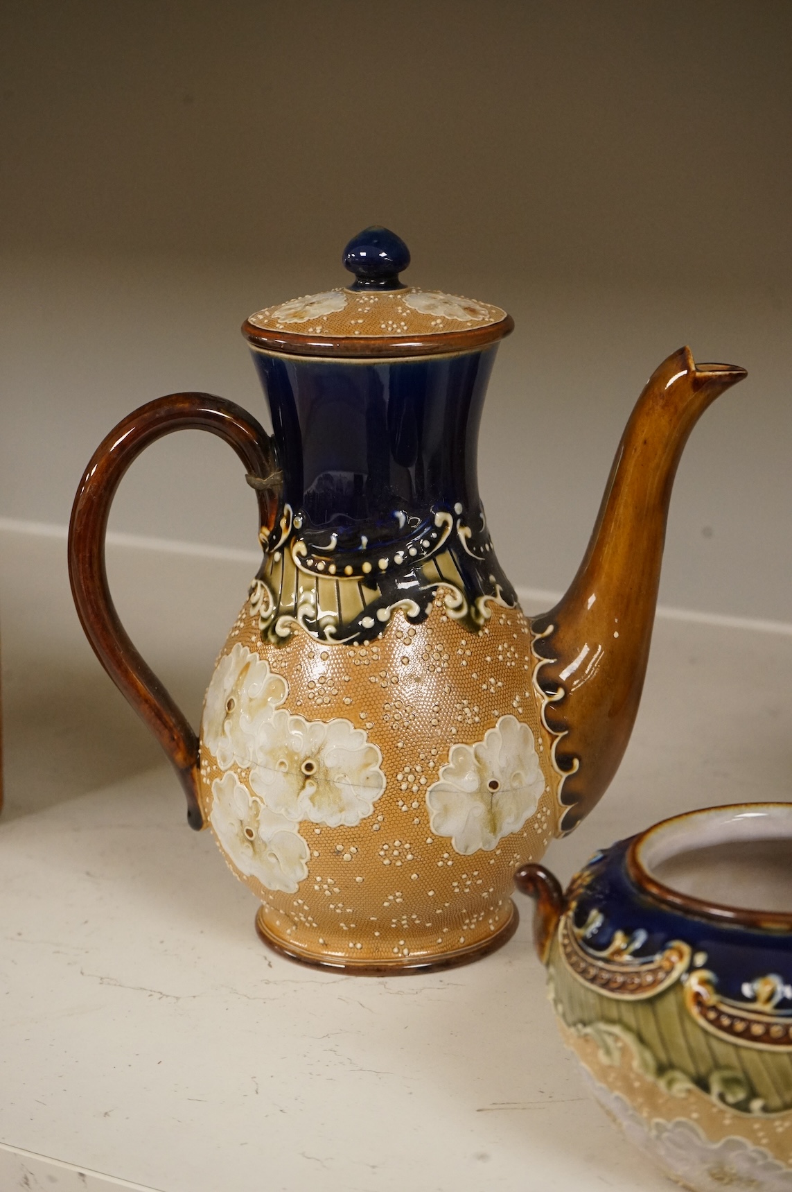 A small collection of Doulton Lambeth stoneware comprising, tea and coffee pots, two jugs and sugar bowl, largest 21cm high